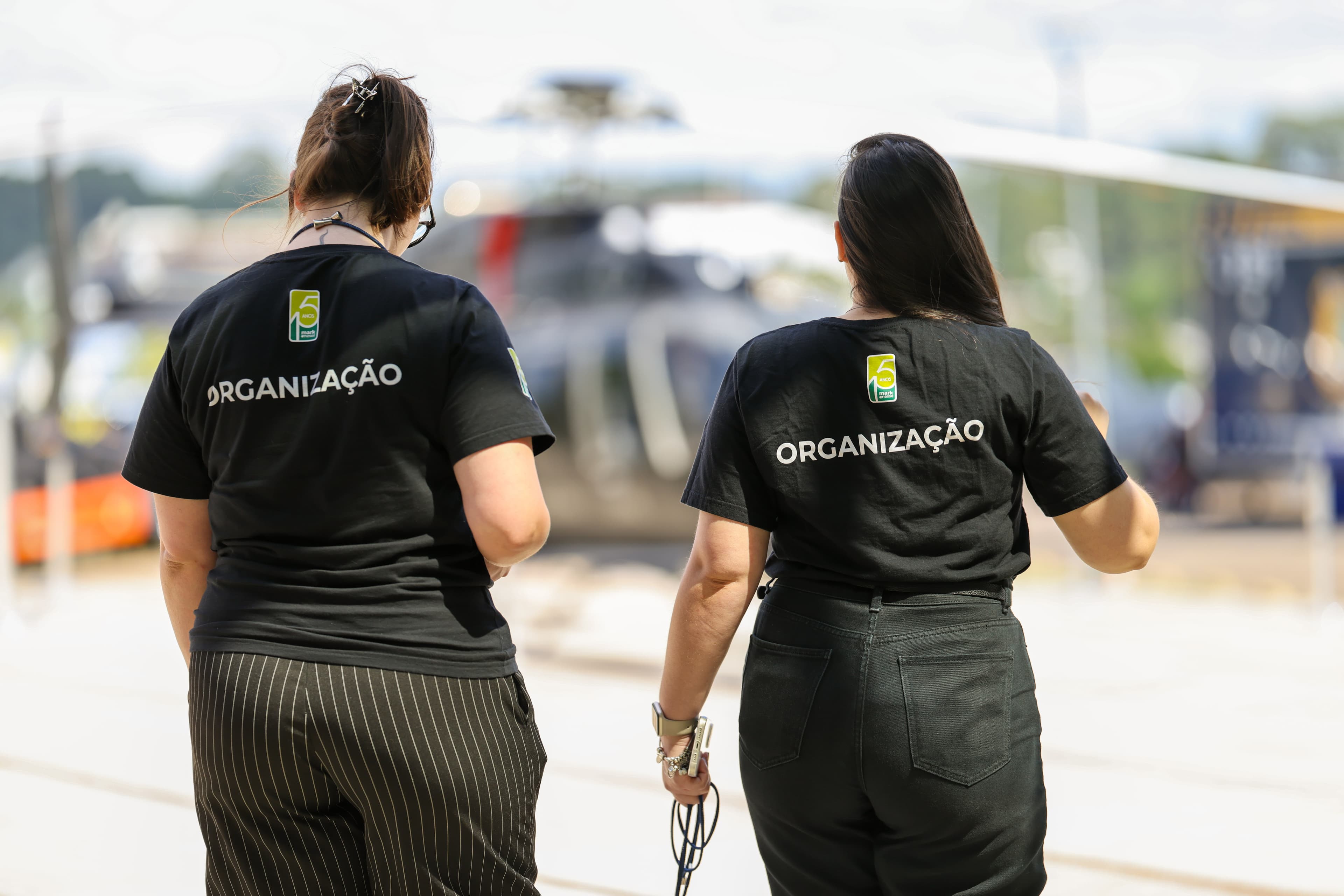Integrantes da equipe com camisetas da organização na área externa do evento