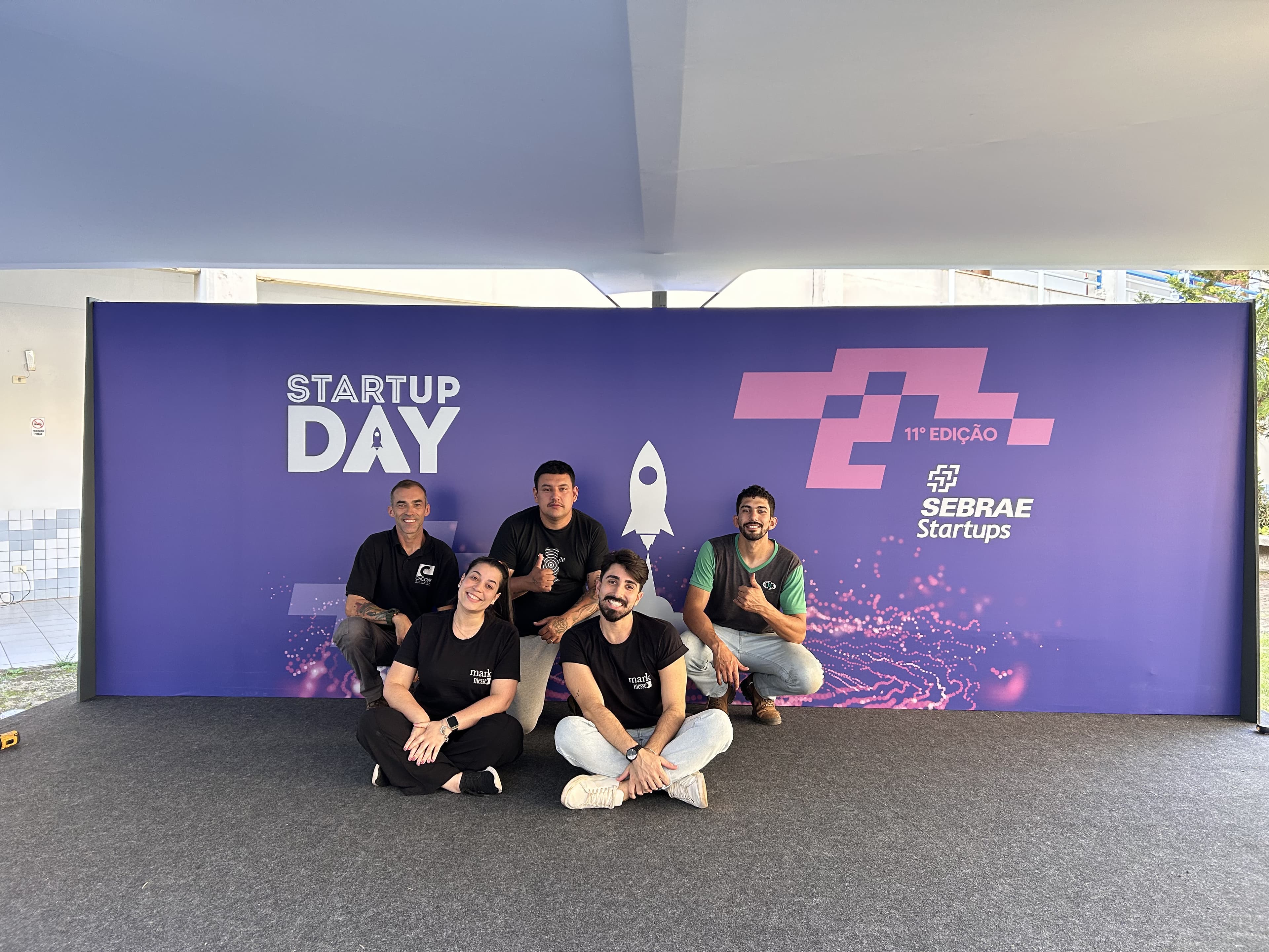 Equipe reunida em frente ao painel do Startup Day